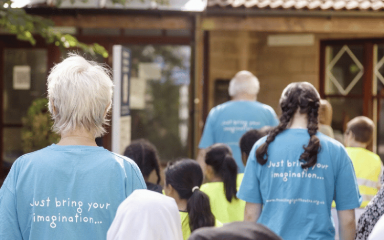 Three Travelling Light staff escorting children from the holiday workshop