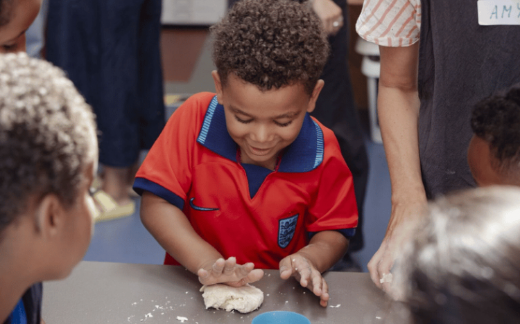 Young child rolling dough with his hands