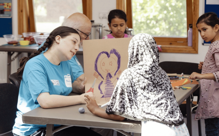 Travelling Light staff holding up a drawing of a superhero to a child